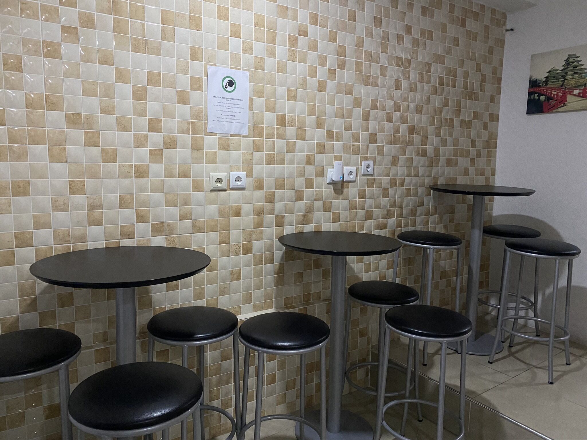 A restroom with tiled walls, multiple round tables, and stools.