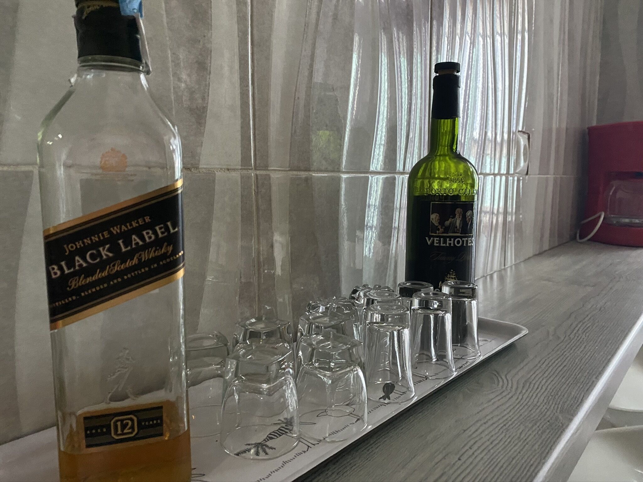 Zwei Whiskeyflaschen auf einem Regal, darunter Gläser.