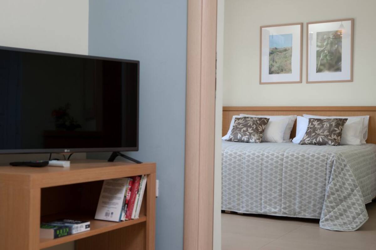A bedroom with a bed, a television on a stand, and a bookshelf.