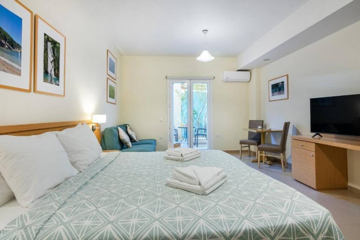 A hotel room with a bed, a desk, a TV, and a balcony with a view.