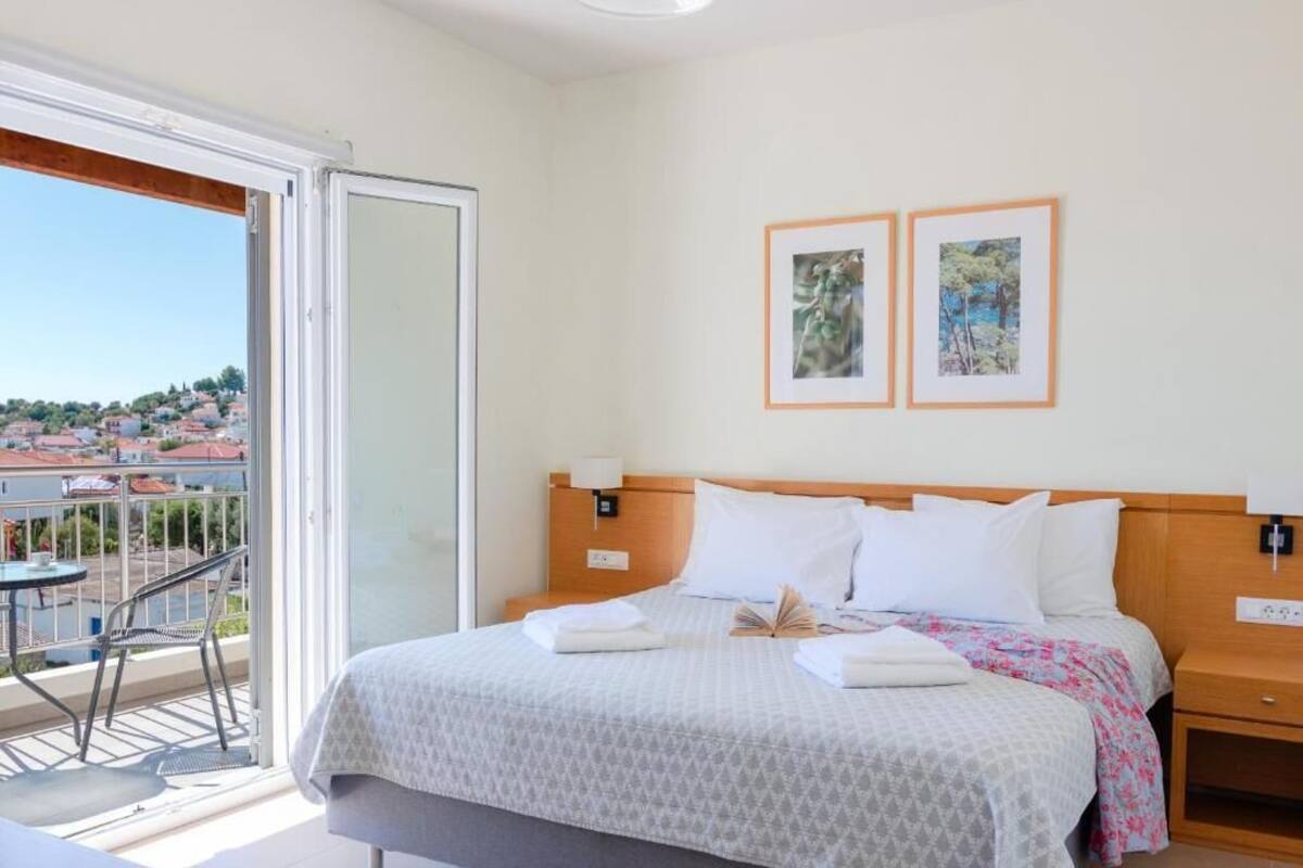 A hotel room with a bed, bedside tables, a balcony with a chair, and two framed pictures on the wall.