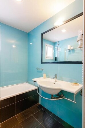 Ein Badezimmer mit Badewanne, Waschbecken und Spiegel.