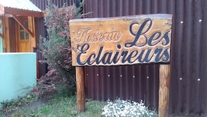 A wooden sign with the text "Hostess Les Cailleaux" in a decorative font, mounted on a post. - Hosteria Les Eclaireurs (Ushuaia)