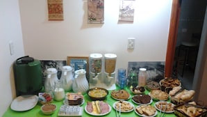 A buffet table with various food items and beverages, a coffee machine, and a sign on the wall. - Hosteria Les Eclaireurs (Ushuaia)