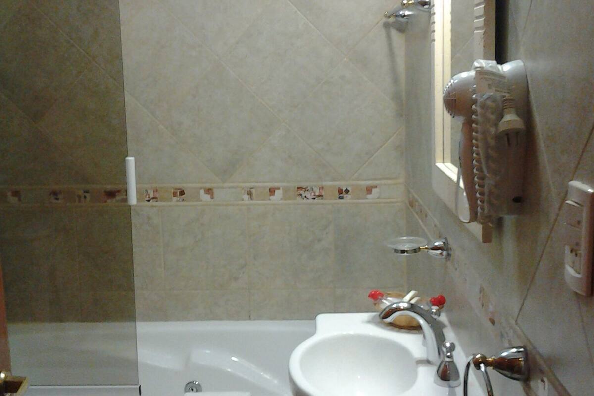 A bathroom with a bathtub, a sink, and a mirror.