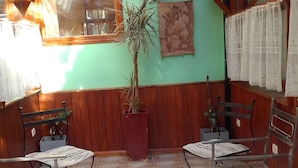 A patio area with wooden furniture and a central table, surrounded by potted plants. - Hosteria Les Eclaireurs (Ushuaia)