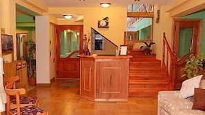A spacious living area with a wooden staircase, a sofa, and a wooden cabinet. - Hosteria Les Eclaireurs (Ushuaia)