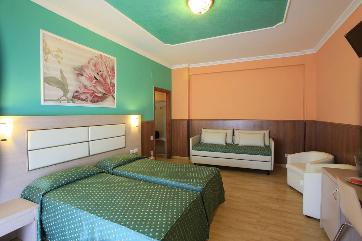 A room with two beds, a desk, and a cabinet.