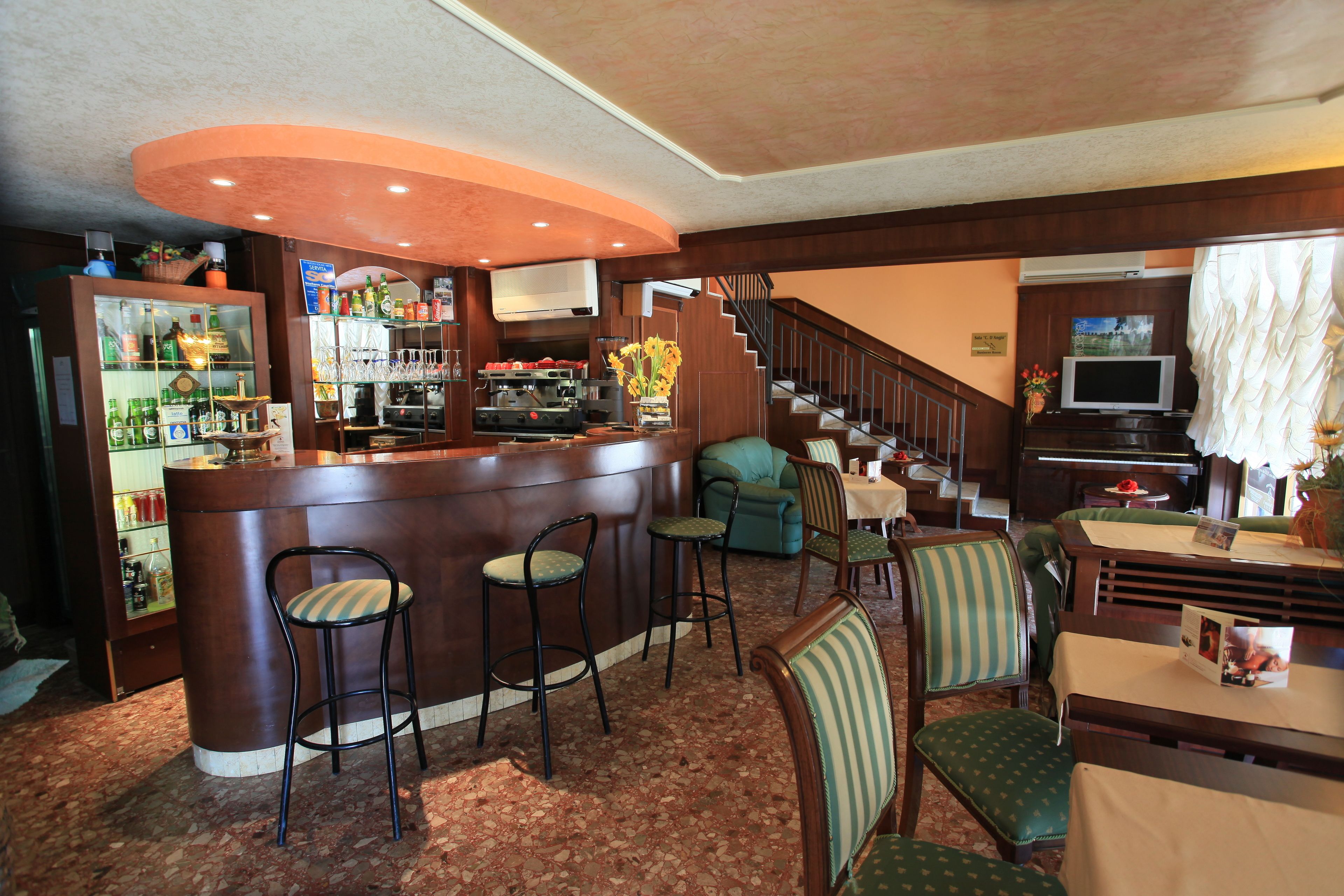 A bar area with stools, a counter, and a staircase leading to another level.