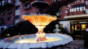 Entrada de hotel con una gran fuente iluminada al frente.