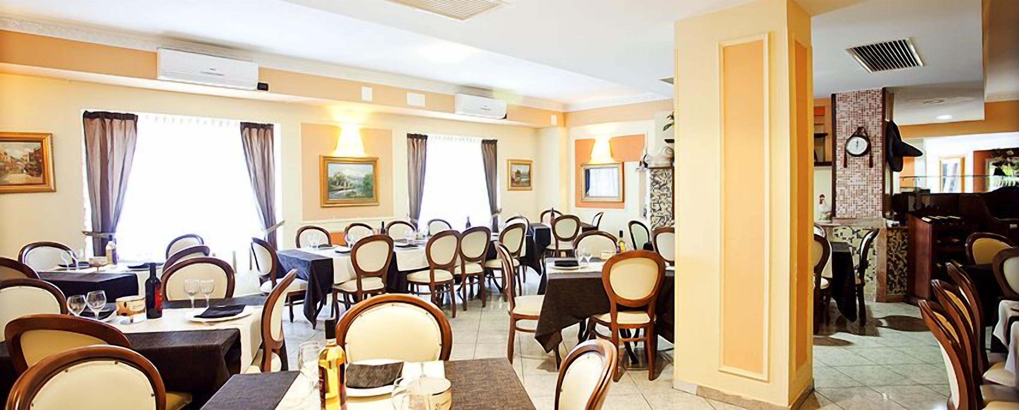 Un restaurante con varias mesas y sillas, unidades de aire acondicionado y cuadros en las paredes.