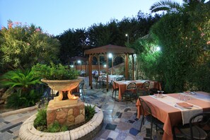 An outdoor patio with tables and chairs, a stone fountain, and a gazebo.
