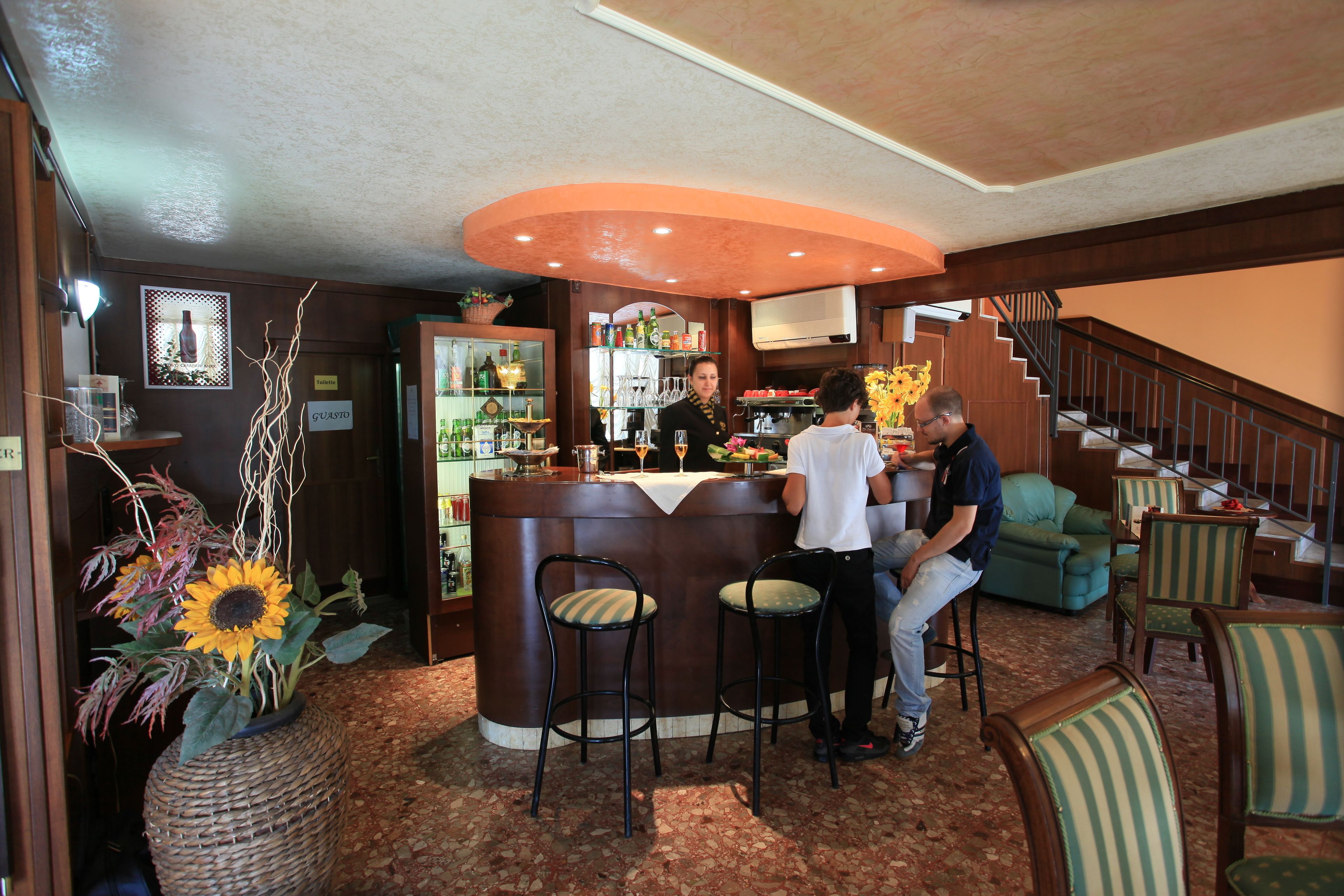 Un espace bar avec un comptoir, des tabourets et un escalier menant à un niveau supérieur.
