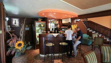 Un espace bar avec un comptoir, des tabourets et un escalier menant à un niveau supérieur.