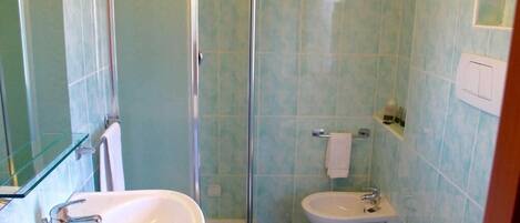 Un baño con cabina de ducha de vidrio, un lavabo y un inodoro.
