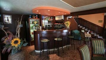 A bar area with a counter, stools, and a staircase.