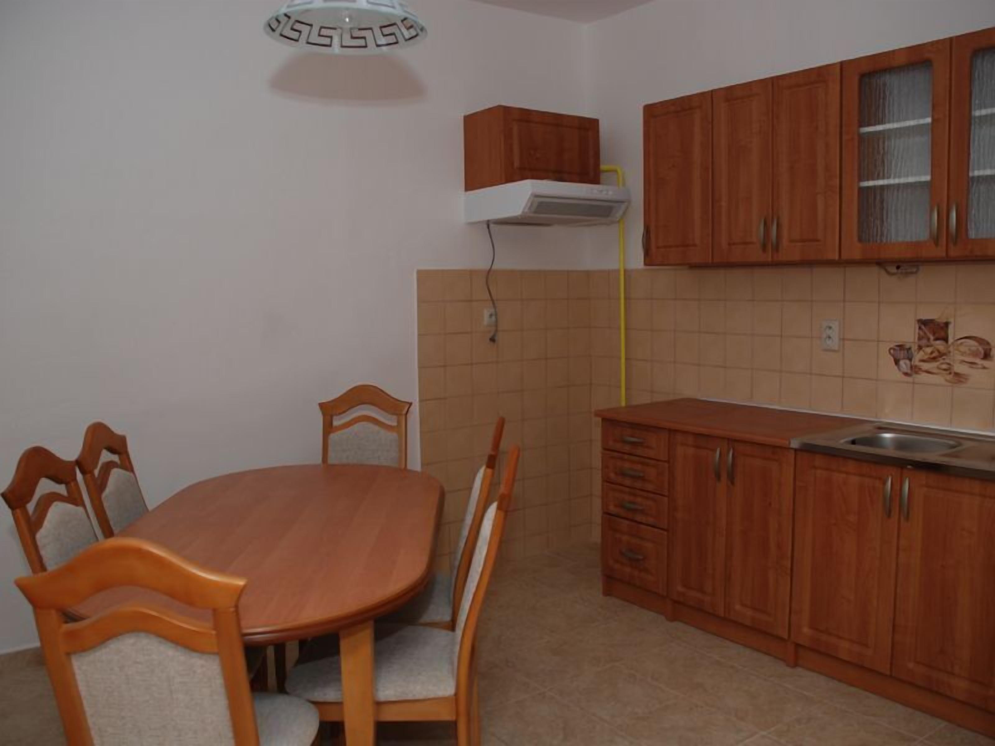 A compact kitchen with wooden cabinets, a dining table with chairs, and a built-in oven.