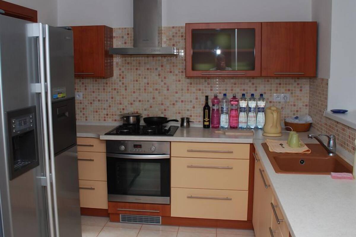 Una cucina compatta con frigorifero, forno, piano cottura e mobili in legno.