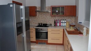 Une cuisine équipée d’un réfrigérateur, d’un four et d’une cuisinière en acier inoxydable, de meubles en bois et d’un dosseret carrelé.