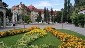 Une cour avec un parterre central, un bâtiment doté d’un toit rouge et une statue.