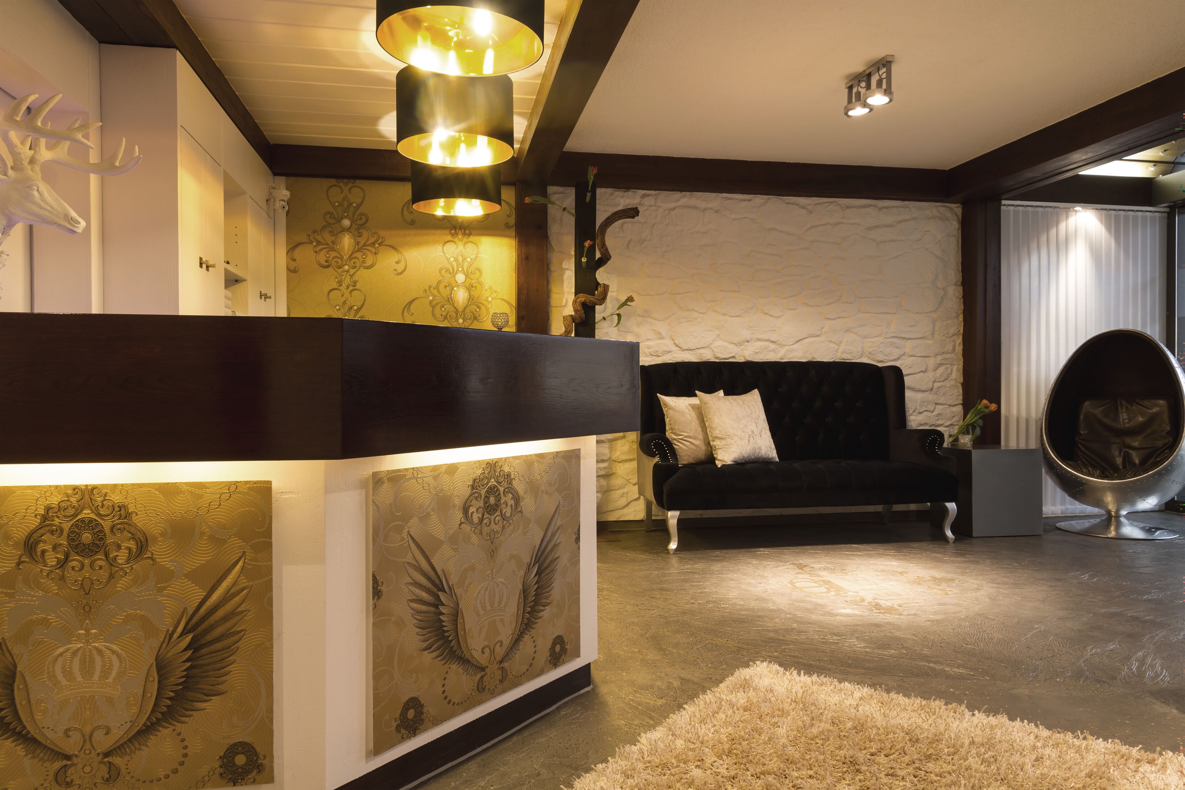 A modern living room with a dark sofa, a unique egg chair, and a decorative wall with a deer head.