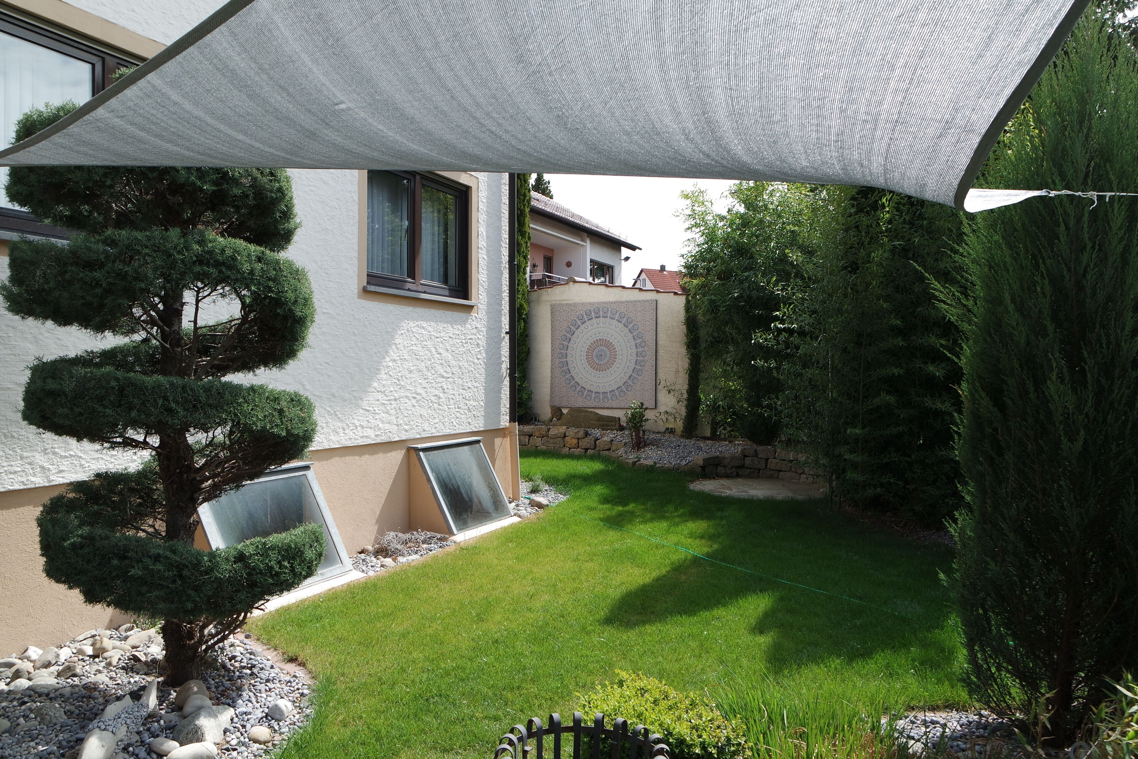 Un jardin bien entretenu, avec une pelouse, un petit arbre et un mur décoratif.