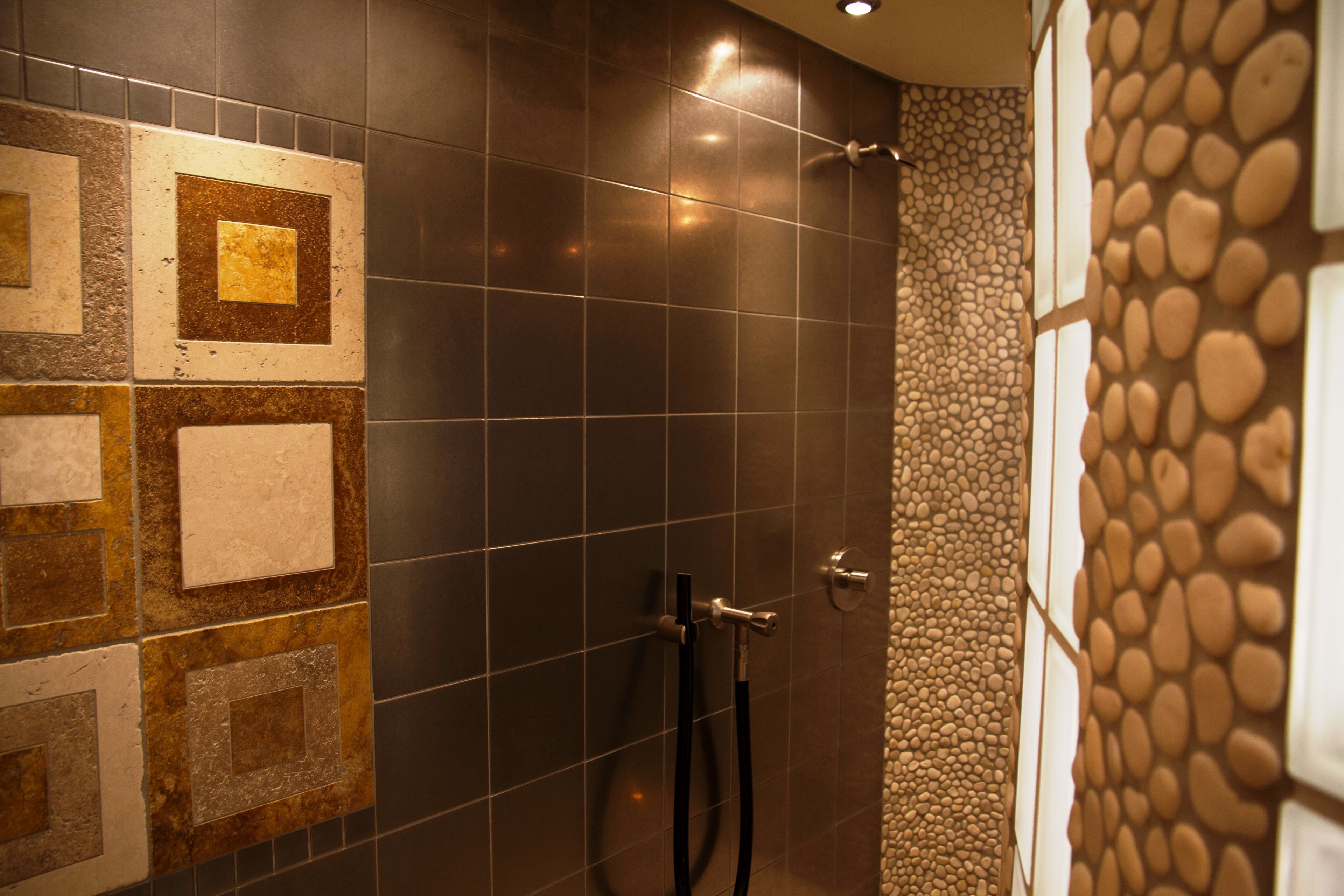 Un área de ducha con paredes de azulejos, un cabezal de ducha y un cabezal de ducha de mano.