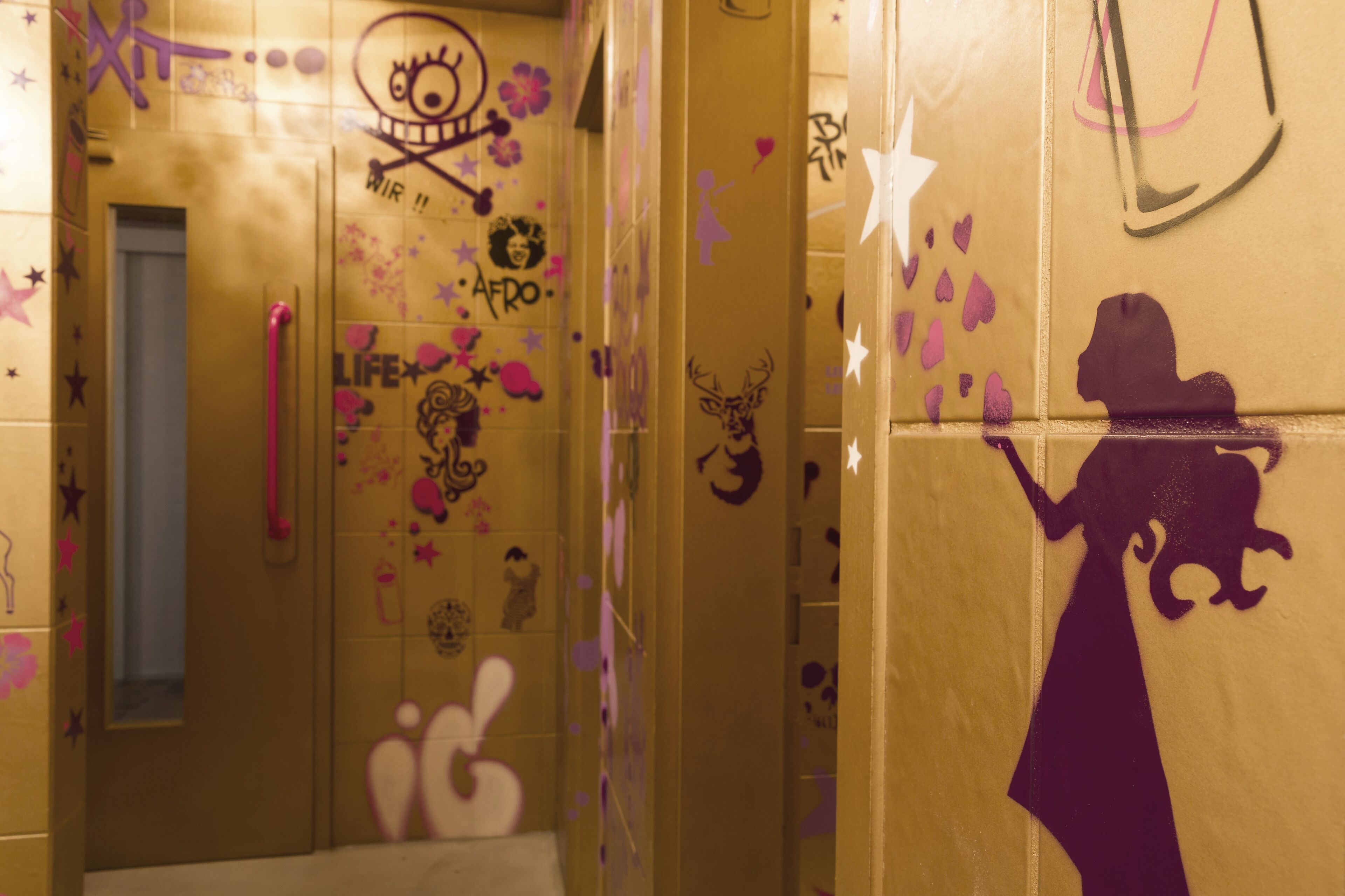 A bathroom with graffiti and a silhouette of a woman on the wall.