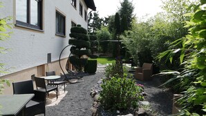 Une cour avec un bâtiment blanc, du mobilier d’extérieur et une végétation bien entretenue.