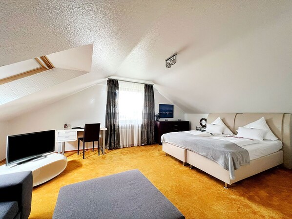 An attic bedroom with a bed, desk, and chair.