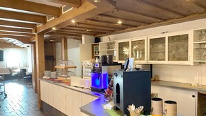 Une cuisine moderne avec des poutres en bois, une machine à café et des meubles de rangement en verre.