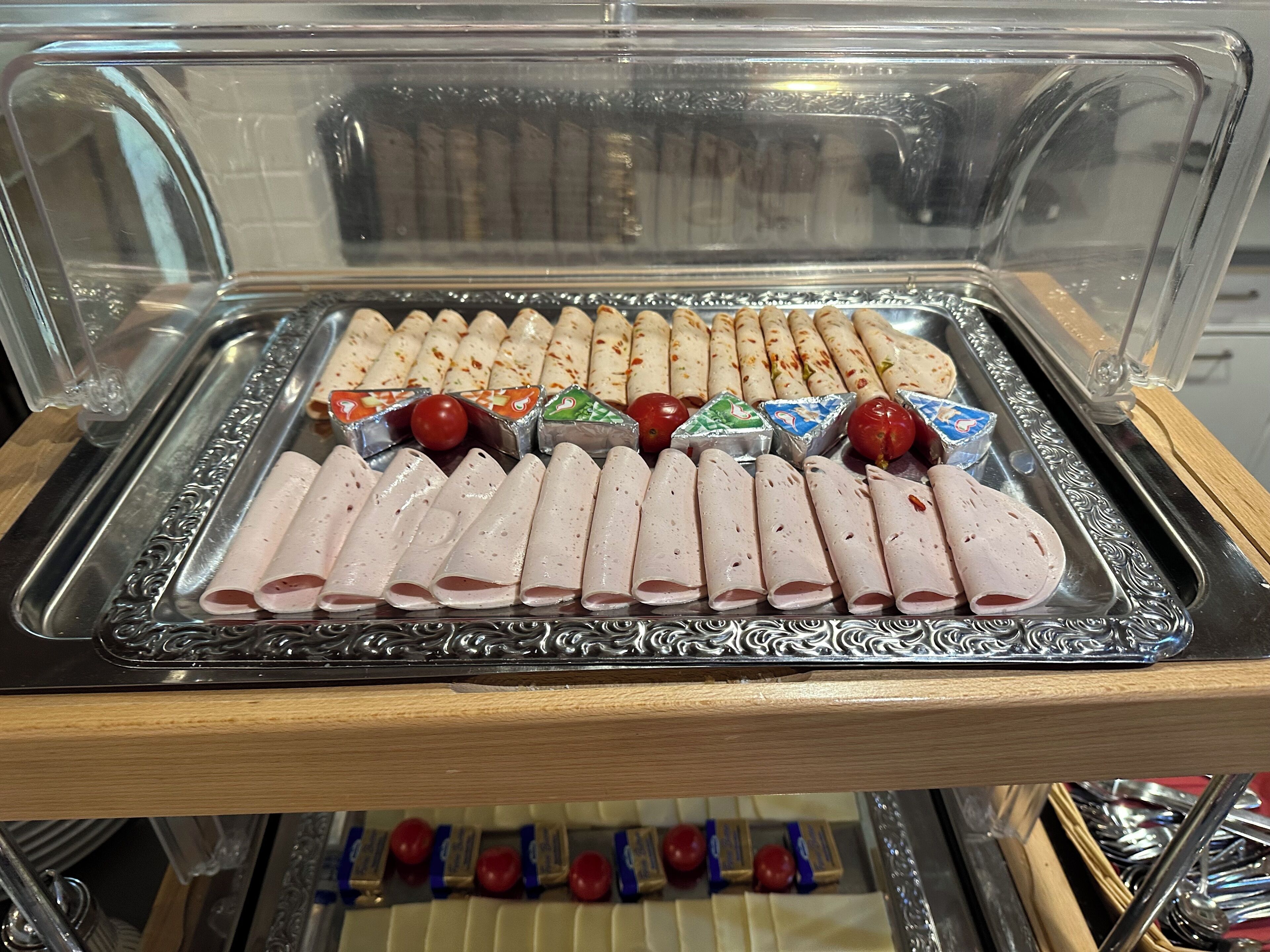 A buffet with neatly arranged food items including meat rolls and various condiments.