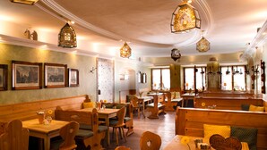A restaurant with wooden furniture, hanging light fixtures, and framed pictures on the walls. - KOLBERBRÄU Posthotel und Gasthaus (Bad Toelz)