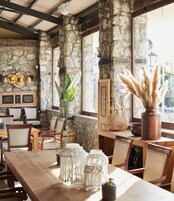 Un comedor rústico con paredes de piedra, muebles de madera y ventanas amplias.