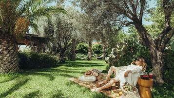 Relax in a serene outdoor setting surrounded by lush greenery and mature trees, perfect for a leisurely day.