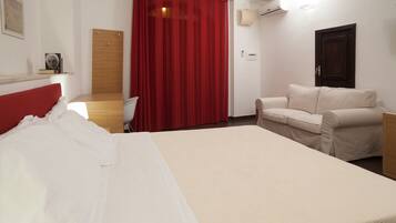 Habitación de hotel con cama, una silla, un escritorio, una cortina roja y una puerta.