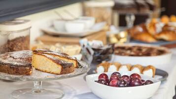 Ein Buffet mit verschiedenen Desserts, darunter ein Kuchen, Gebäck und eine Schale Kirschen.