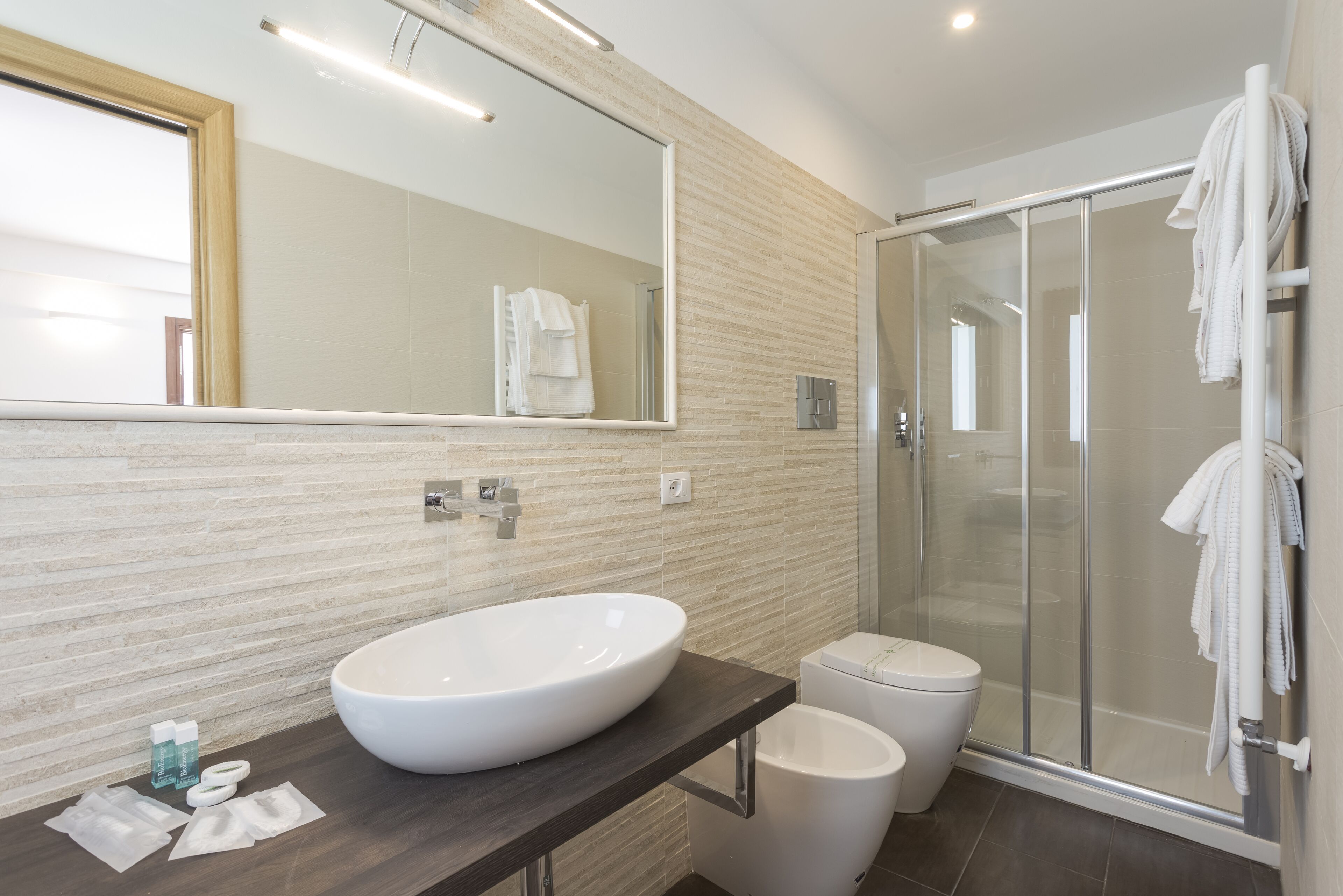 Une salle de bain moderne avec un grand lavabo ovale, des toilettes et une douche à parois de verre.