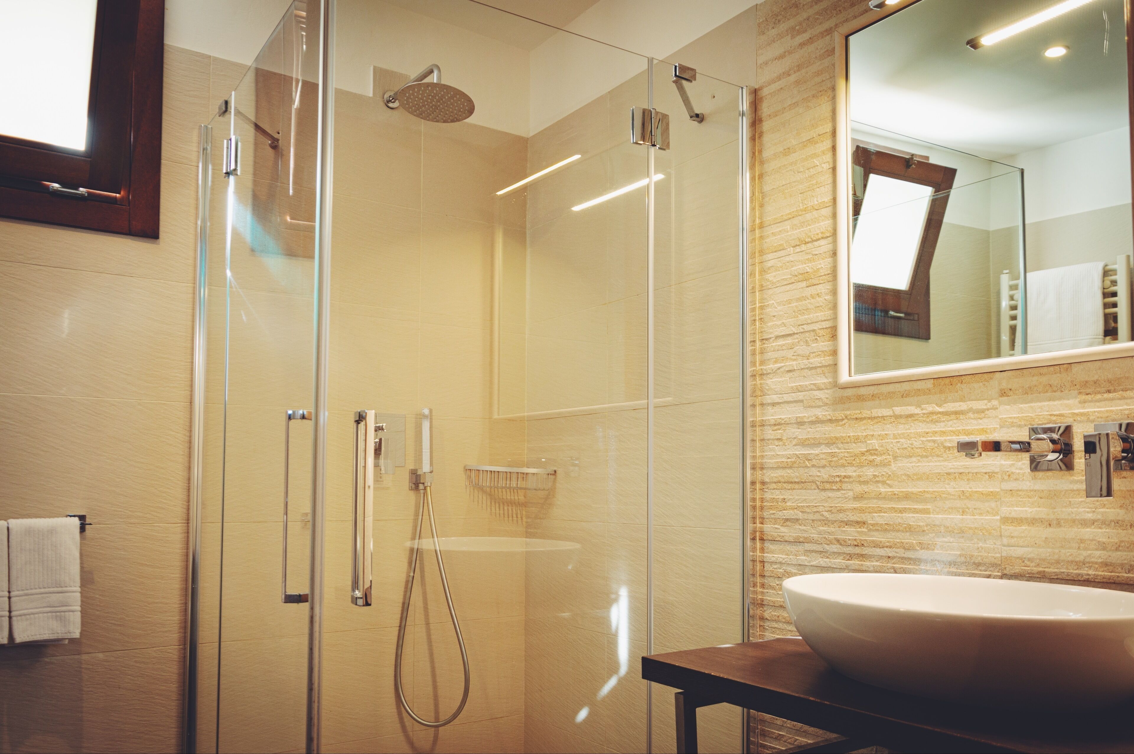 A modern bathroom with a glass-enclosed shower, a large sink, and a mirror.