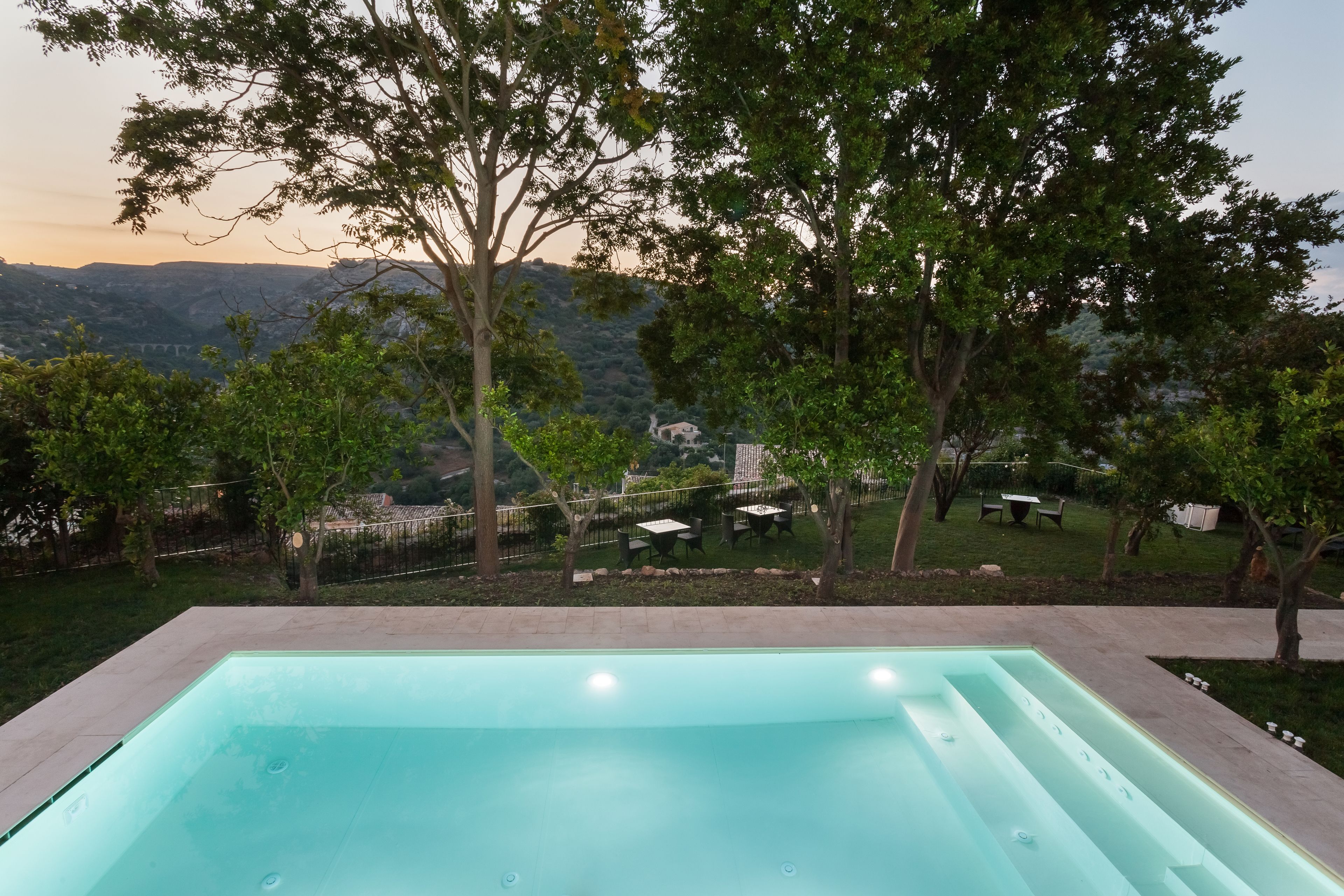 A rectangular pool with a clear edge, surrounded by a low stone wall and trees.
