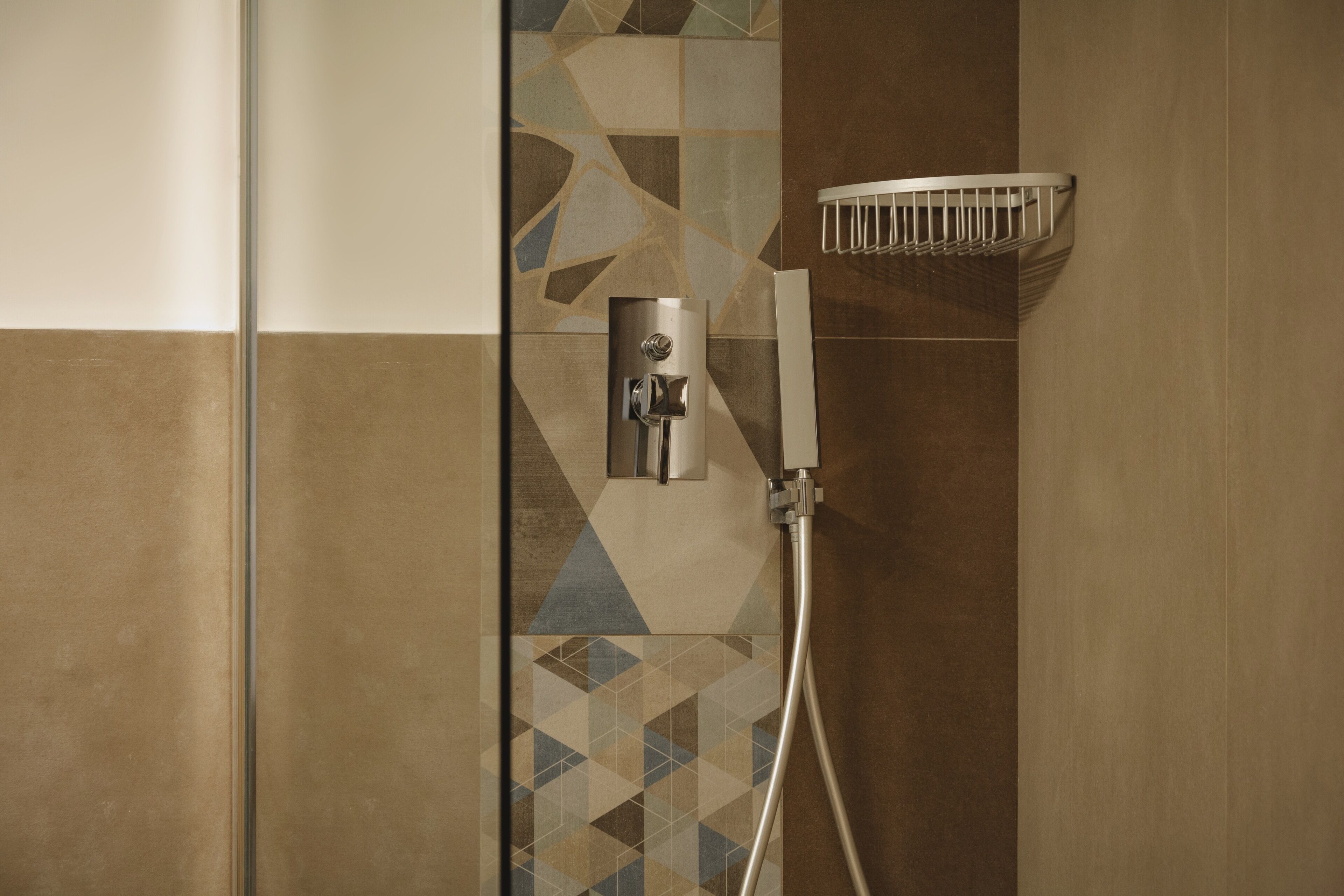 Une douche équipée d’un pommeau de douche à main et d’un panneau de commande fixé au mur.