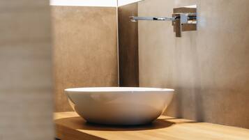 Une salle de bain moderne avec un grand lavabo blanc posé sur un comptoir en bois, un robinet chromé et un miroir fixé au mur.