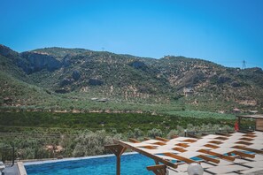 A pool area with wooden loungers and a view of a mountainous landscape. - Natureland Efes (Selçuk)