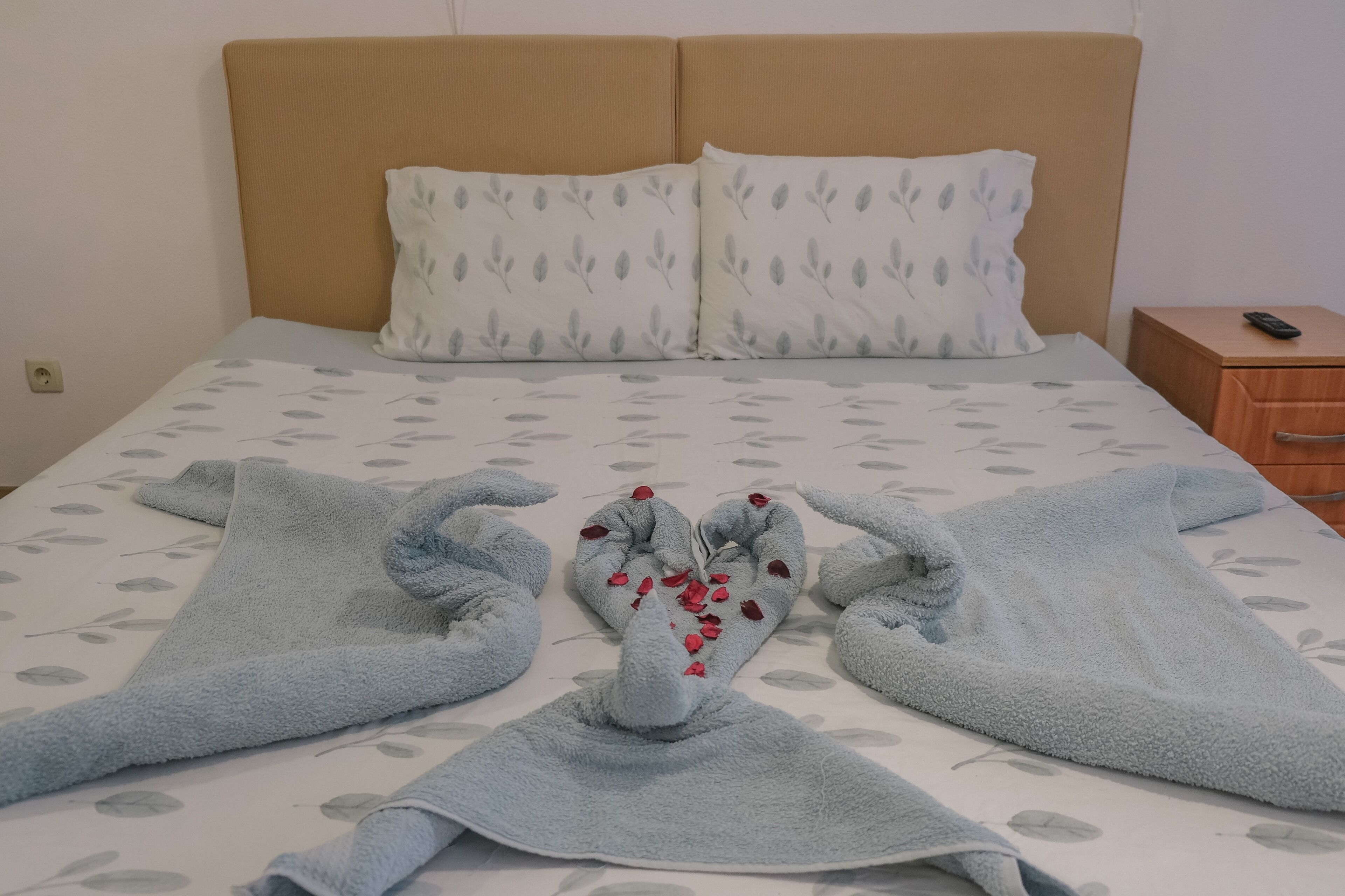 Una cama bien hecha con una colcha estampada de flores y dos almohadas.