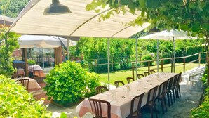 An outdoor dining area with a long table set for six, surrounded by chairs. - Locanda da Marco (Pignone)