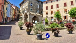 A cobblestone square with historic buildings, a stone archway, and potted plants. - Locanda da Marco (Pignone)