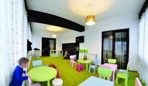 A children's playroom with green and pink furniture, a chalkboard, and a large window. - Pensiunea Casa Humor (Gura Humorului)