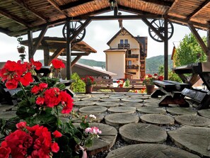 A wooden gazebo with a view of a mountain house.