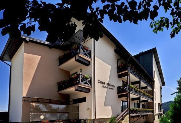 A multi-story building with balconies, a sign reading "Casa Humor", and a stone facade. - Pensiunea Casa Humor (Gura Humorului)
