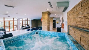 A spa area with a hot tub, stone walls, and a view of the outdoors. - Pensiunea Casa Humor (Gura Humorului)